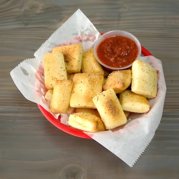 Golden-brown garlic knots with herbs and parmesan cheese, served with a side of marinara sauce.