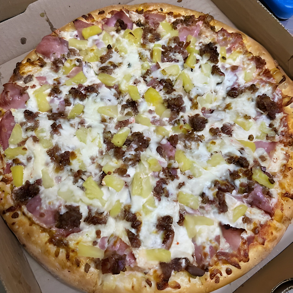 A Bella Pizza Hawaiian pizza with ham, pineapple, and ground beef in a cardboard box.