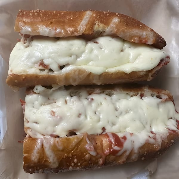 Two cheesy pizza subs with melted mozzarella and tomato sauce on toasted bread.