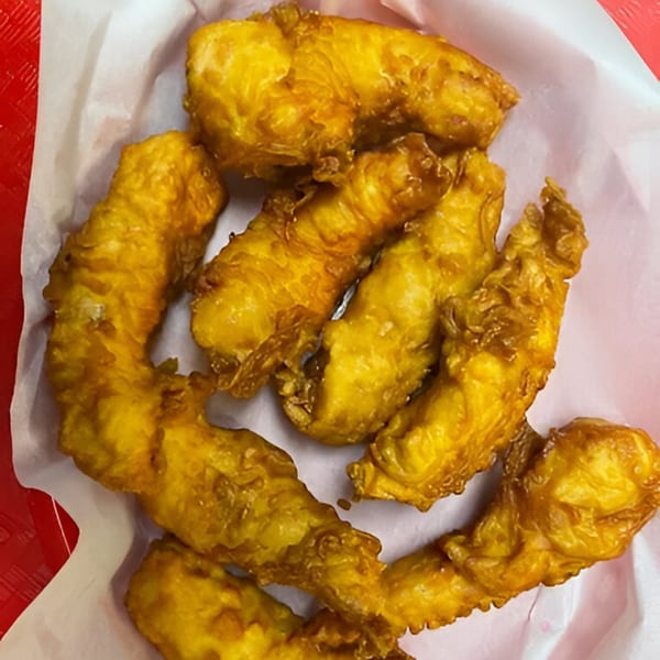 Golden-brown fried chicken tenders or fish fillets, served in a white paper-lined basket.