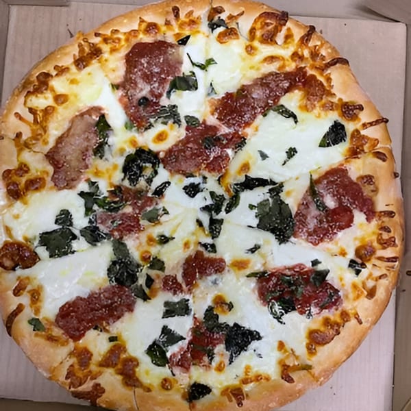 A Bella Pizza pie with white cheese, pepperoni, and spinach in a cardboard box.